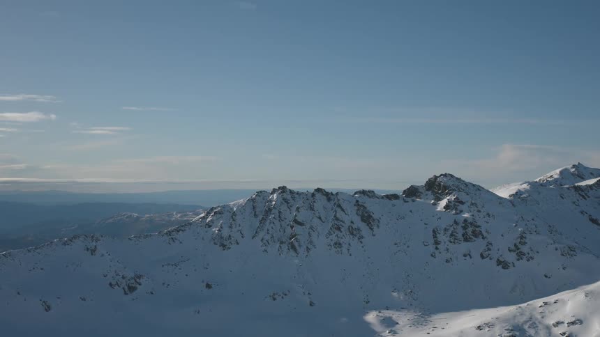 Aerial of a snowcovered mountain range on a mostly sunny day