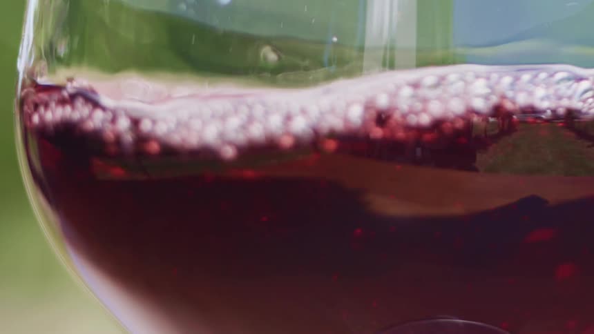 Red wine is being poured into a wine glass in slow motion