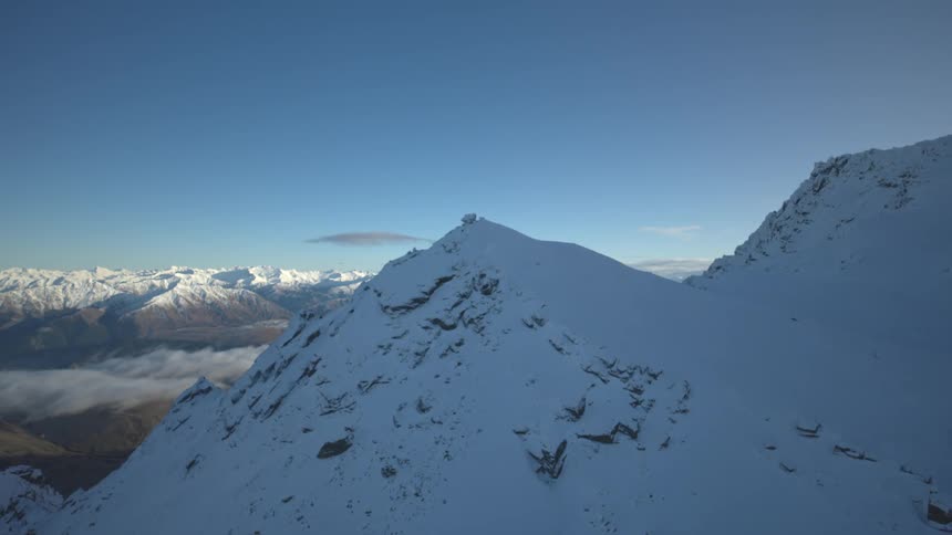 Snow covered mountains tower over wispy clouds