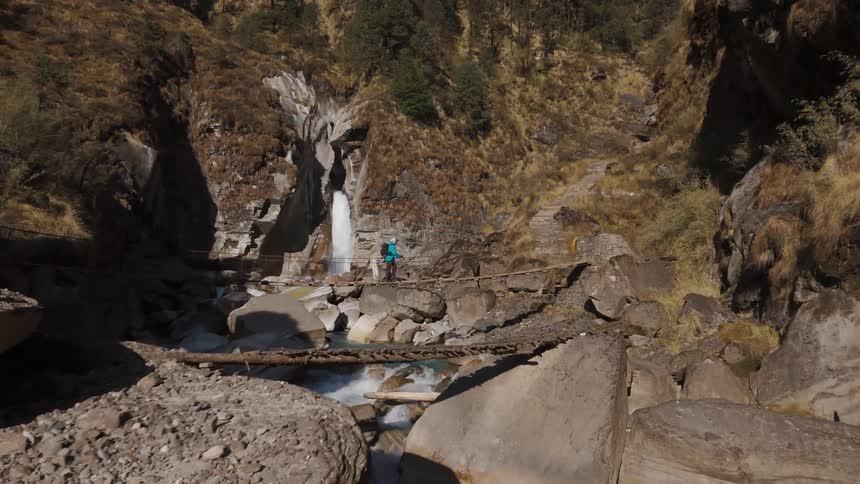 A man is hiking on the bridge over the stream