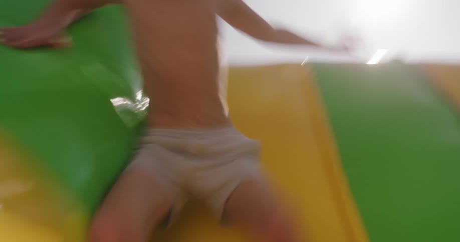 Young boy jumps and bounces down an inflatable slide