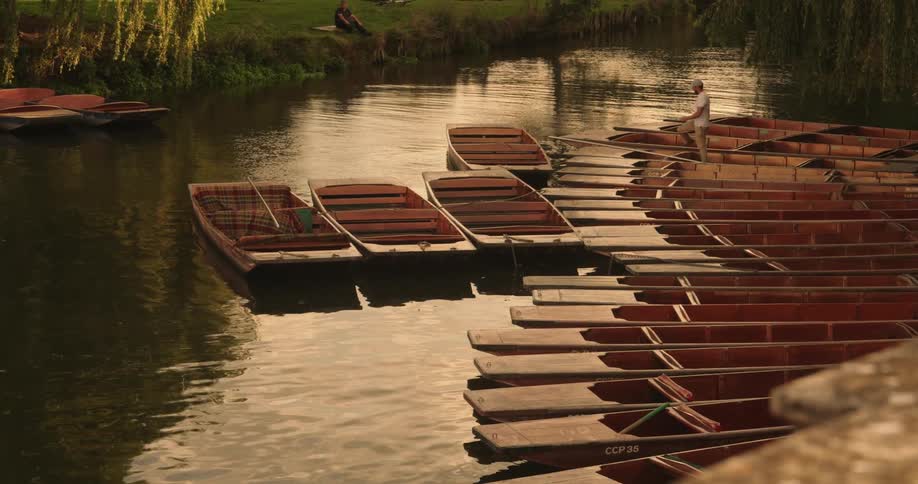 A man walks on a boat near a river shore