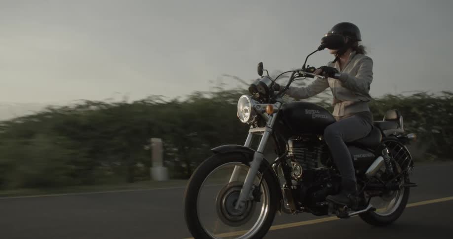 Woman driving a motorcycle down a tree lined road