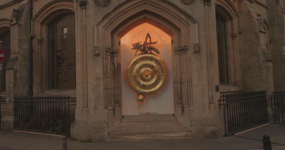 A golden round object with a large golden cricket on the top and there are lights moving on the round object