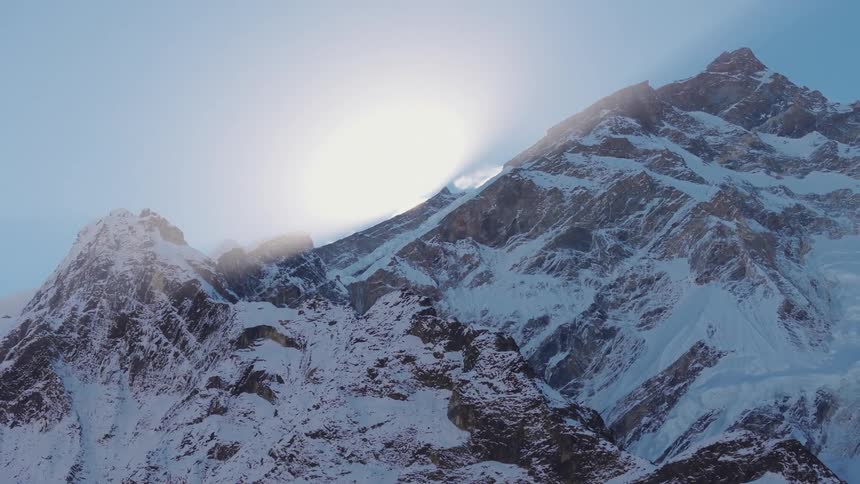Sun reflection behind a mountain covered in snow