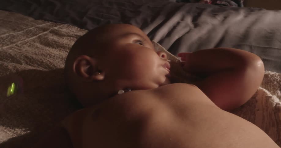 Naked baby lying down and soap bubbles falling