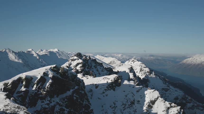 A partially snow covered mountain sits near bigger mountain ranges