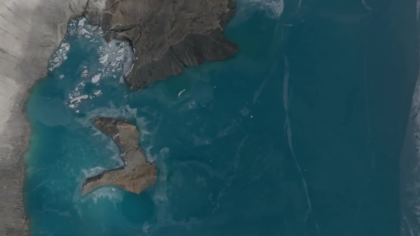 Partially frozen water around an island and a rocky coastline