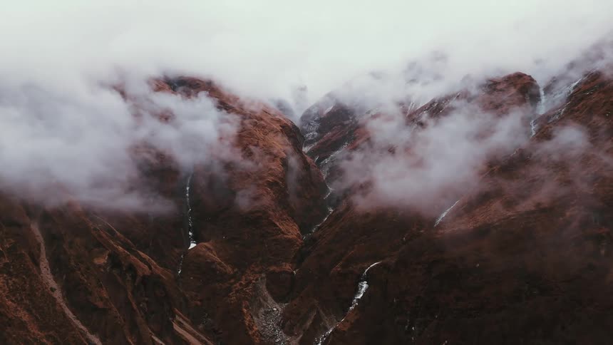 Brown misty mountains with water traveling down the canyon