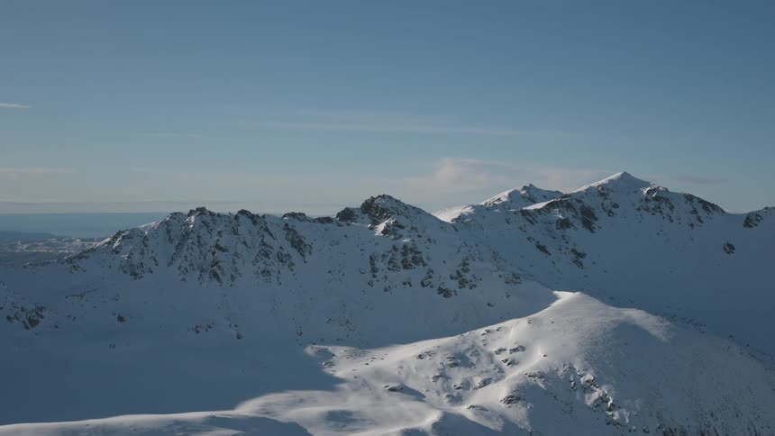 Snowy mountain peaks under a mellow blue sky