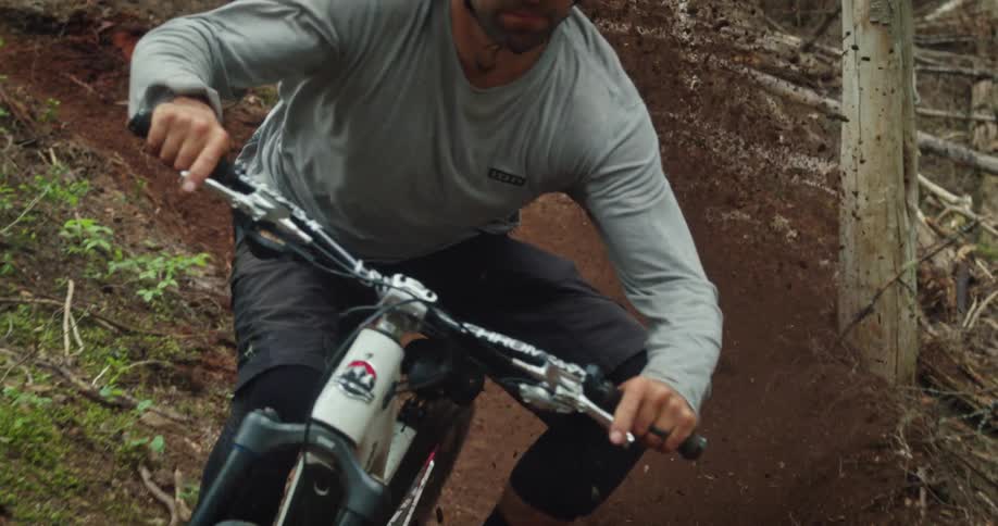 Athlete rides mountain bike through loose corner on trail causing massive explosion of dirt and loam