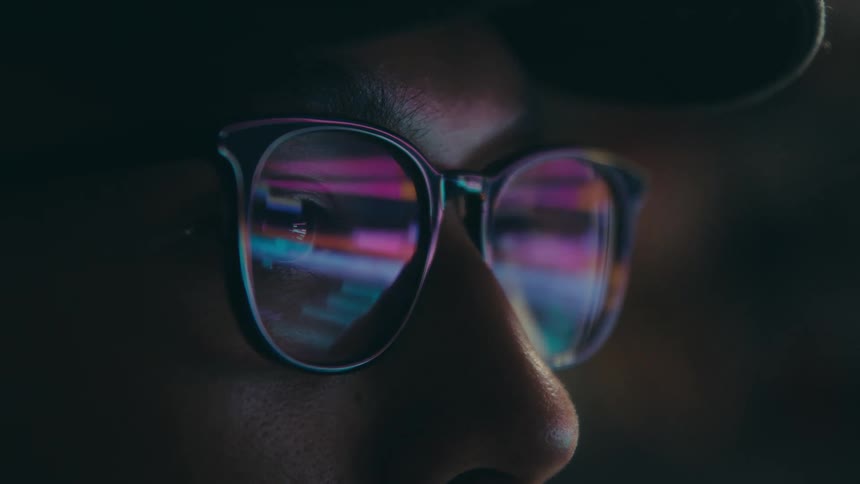 Screen reflecting in the glasses of a man