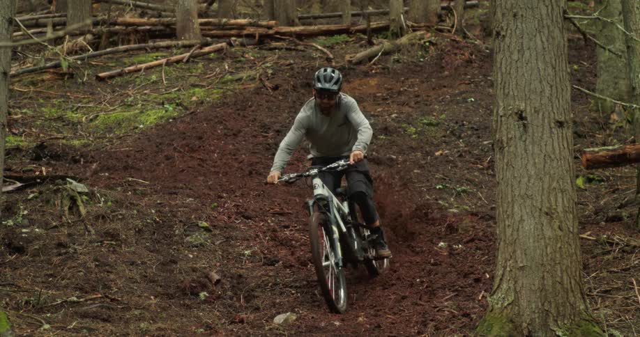 A mountain bike athlete carves through loose dirt on a fresh forest trail