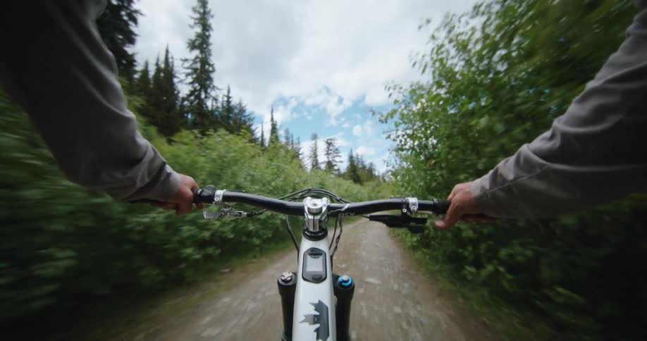 Point of view of a persons arms holding onto the handlebars of a bicycle as they pedal up an alpine access road