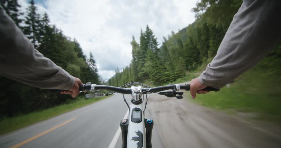 A person rides a bike on a paved highway before turning to climb up the dirt road