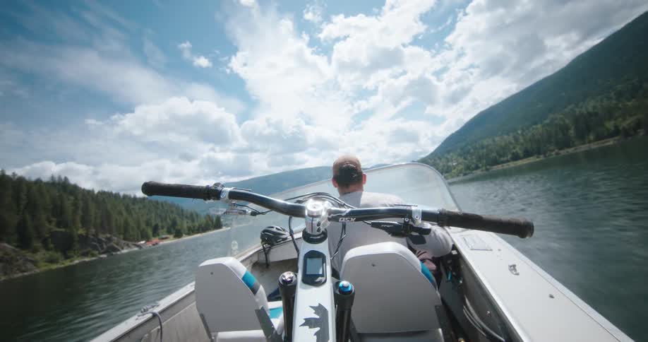 A man drives a boat on a lake on a partially sunny day