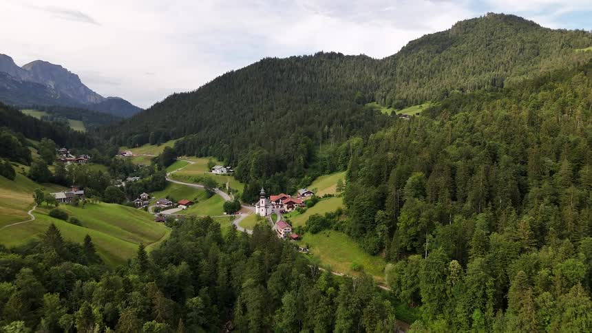 Aerial view of a rural landscape with houses scattered among wooded hills and green fields