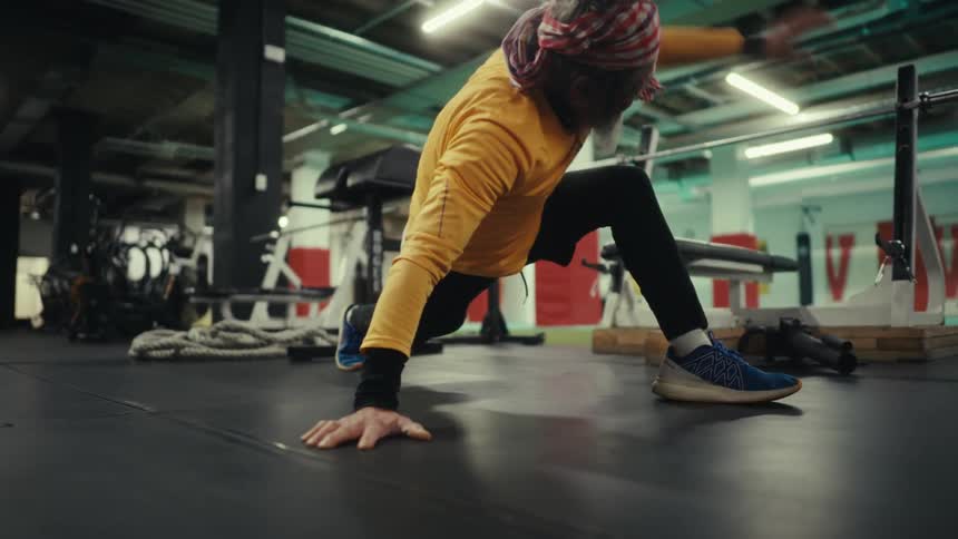 Man in a gym stretching his legs and arms