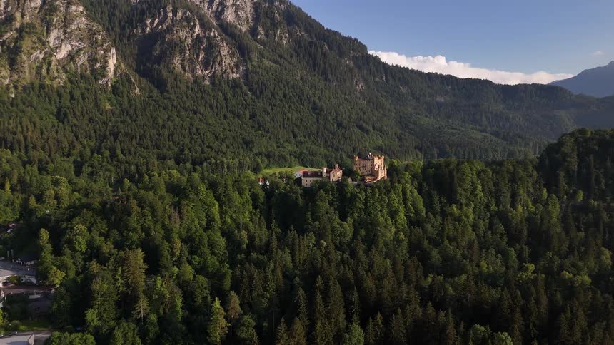 Neuschwanstein castle perched on a rugged hill in bavaria germany surrounded by forests and framed by mountainous terrain