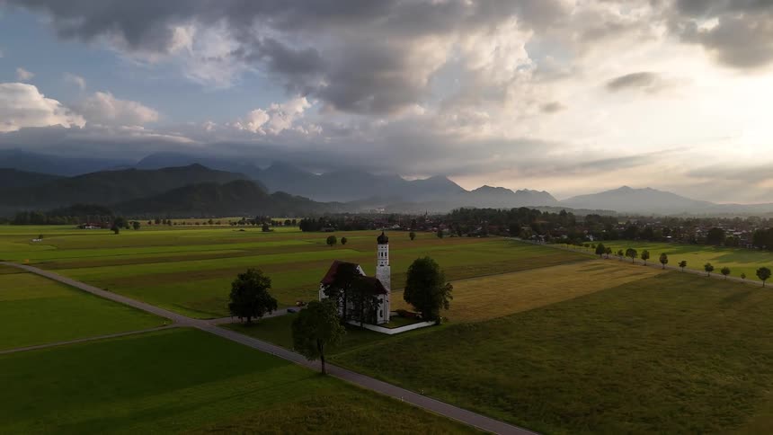 Fields surround church near an intersectionoutside of town on a cloudy day