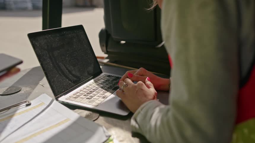 Woman typing on a laptop at an industrial site