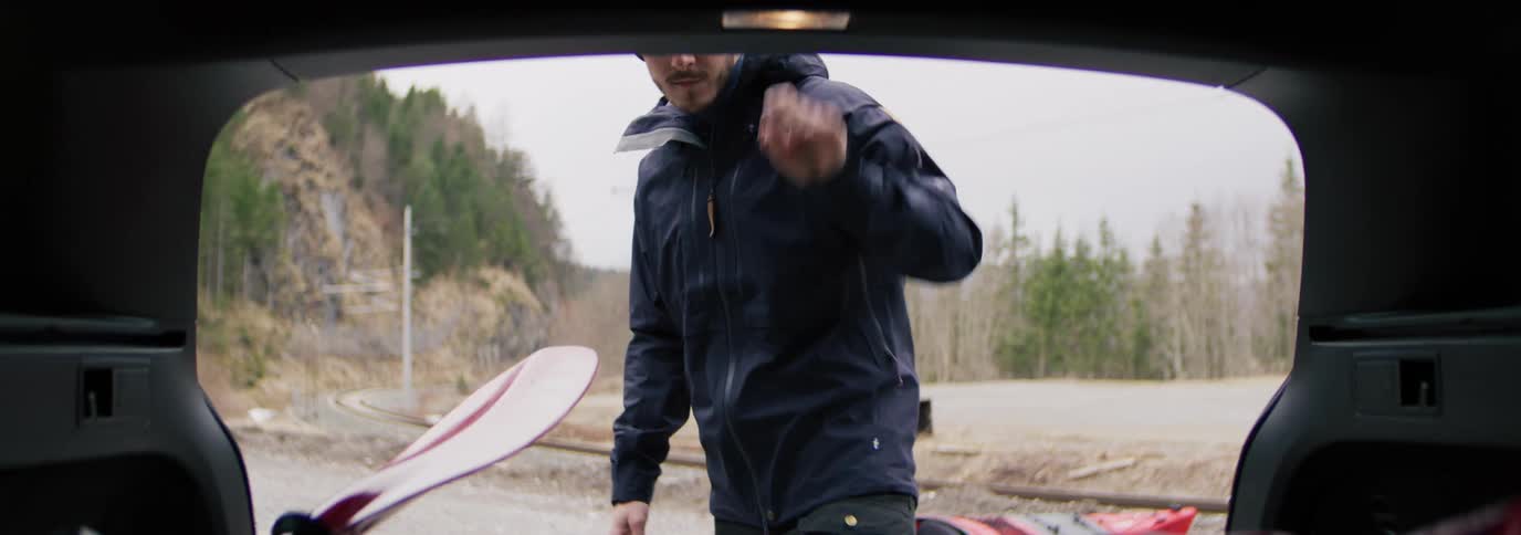 A train passes by a man removing oars from a vehicle to go kayaking