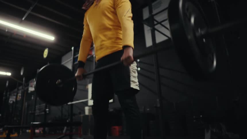 Gray bearded man lifts a weight bar while working out in the gym