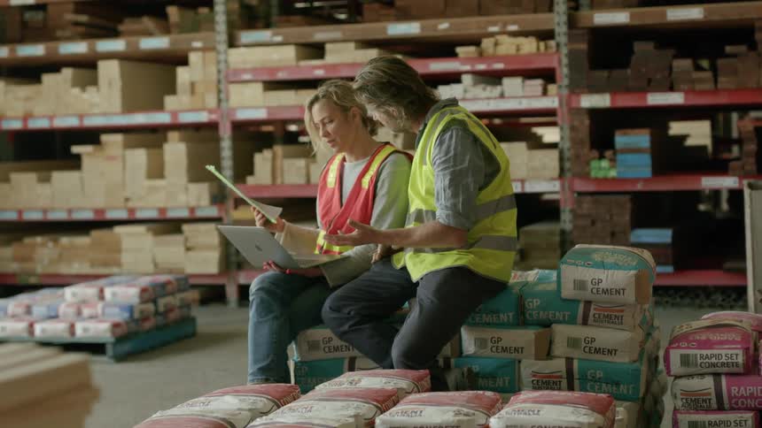 Coworkers work together in a warehouse filled with concrete and cement