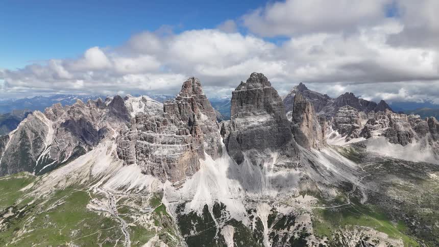 An aerial view of mountain peaks with sharp cliffs and ridges under a blue sky