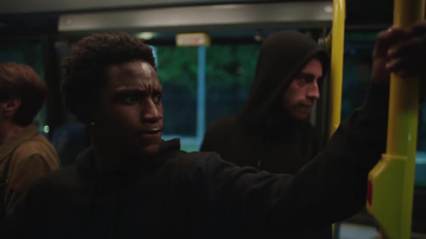 Two men on public transportation look around before exiting the stopped vehicle
