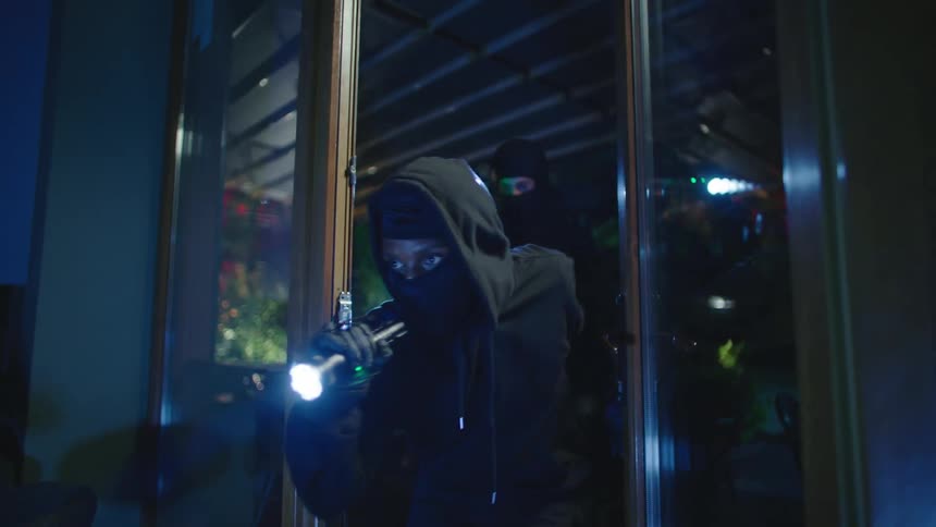 Two people break into a business at night walking inside carefully