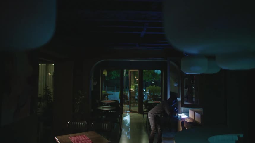 Two burglars break into a restaurant and being looking for things to steal