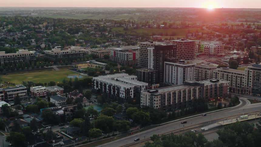 Sun sits on the red horizon while traffic flows along a highway passing apartment buildings