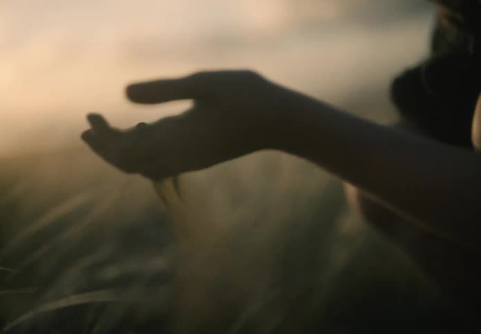 A girl lifts dirt from the field and drops it