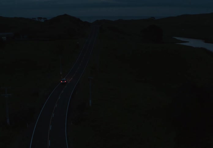 A car drives down a dark roads left lane at night