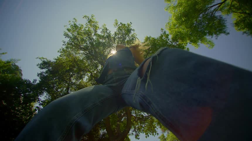 Bright sun shines onto female dancer dancing between the trees