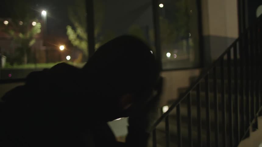 Two suspicious males put on masks while walking down an interior staircase