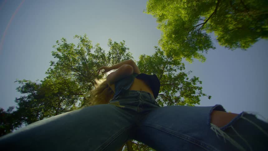 Blonde woman in jeans dancing in a place with trees in the open