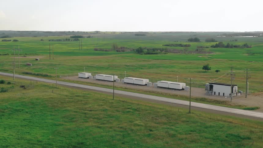 Aerial view of a fenced facility with rows of batteries