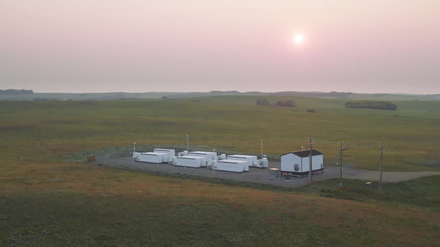 Aerial view of a fencedin facility with large white industrial units arranged in rows