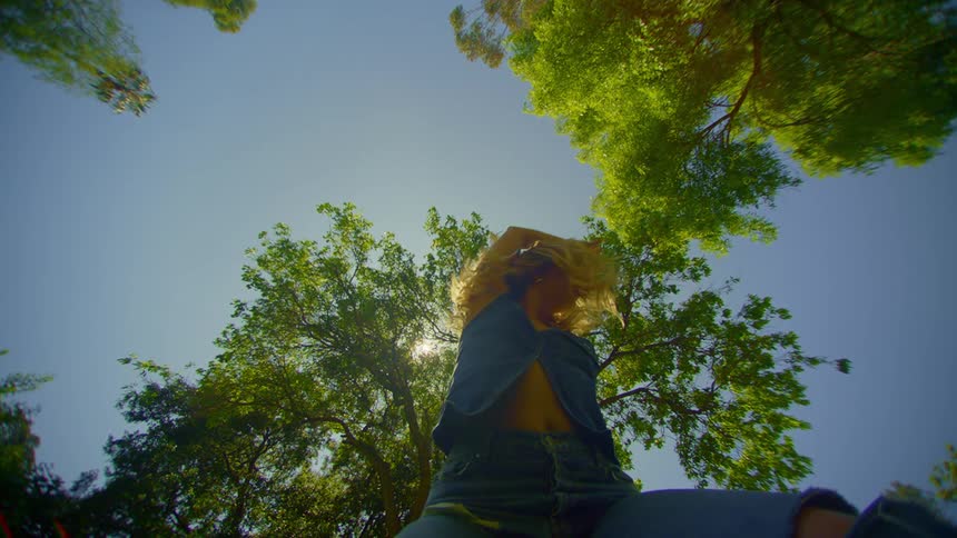 A woman dances in slow motion in a park on a summers day