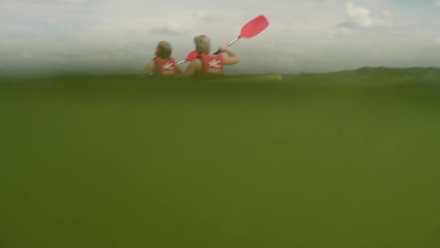 Two women kayak on the lake under a blue sky