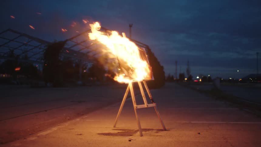 Painting burning on an easel in a parking lot