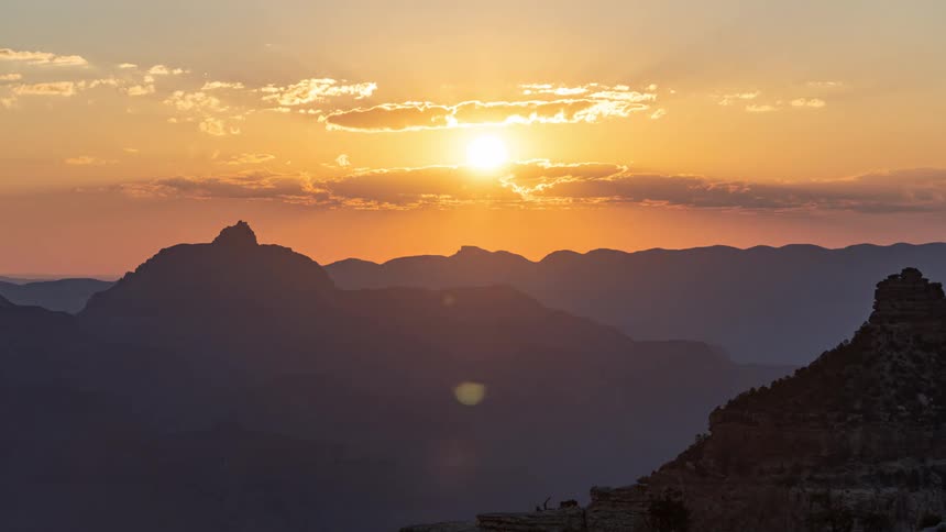 Grand canyon on a day with the sun emerging from behind the mountains and brightening the environment
