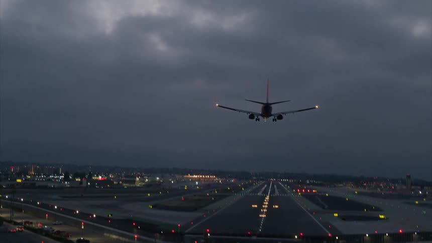 A plane lands on the runway on a cloudy day