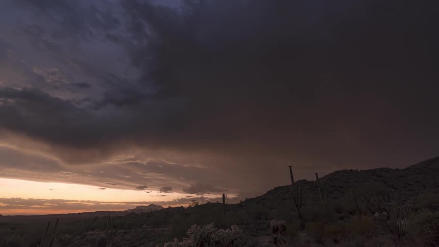 Timelapse footage captures distant rain falling from storm clouds over the desert landscape