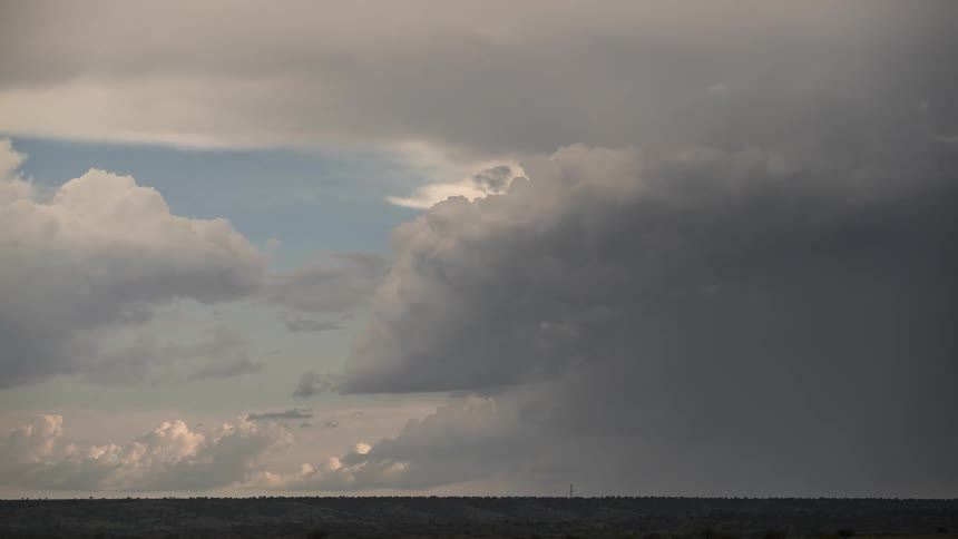 Timelapse footage captures distant rain falling from storm clouds over the desert landscape