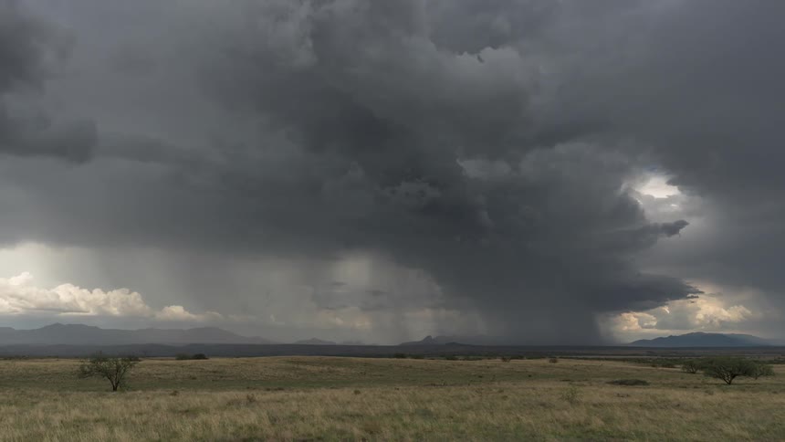 Landscape of a field with mountains on the horizon and a cloudy sky
