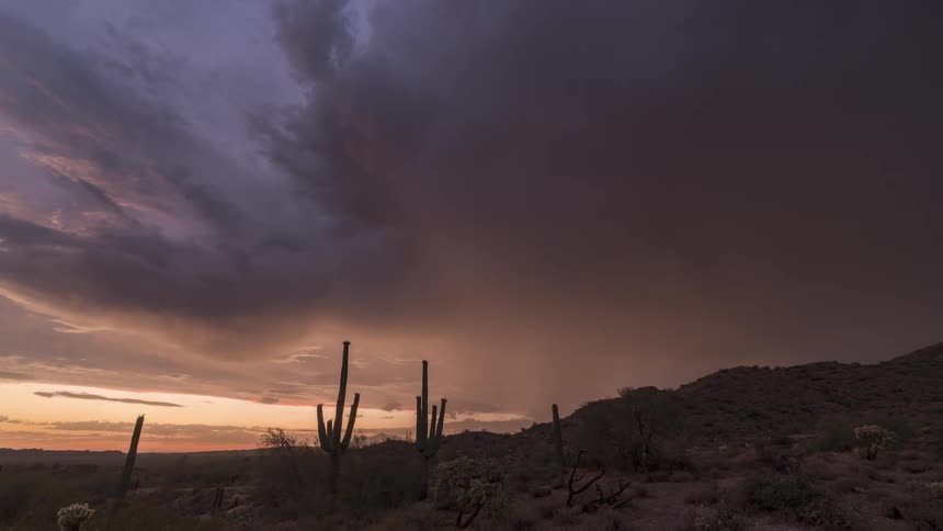 Dark storm clouds with lightening move across the desert blocking the sun