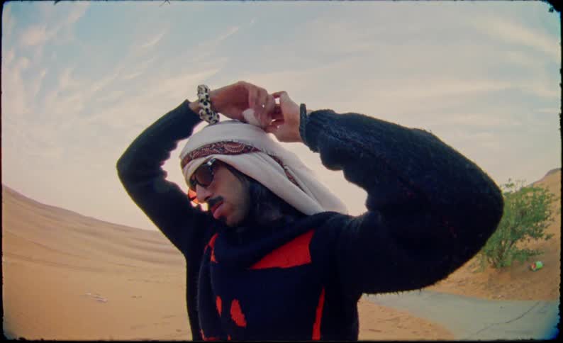Man wraps a headdress on his head in the desert